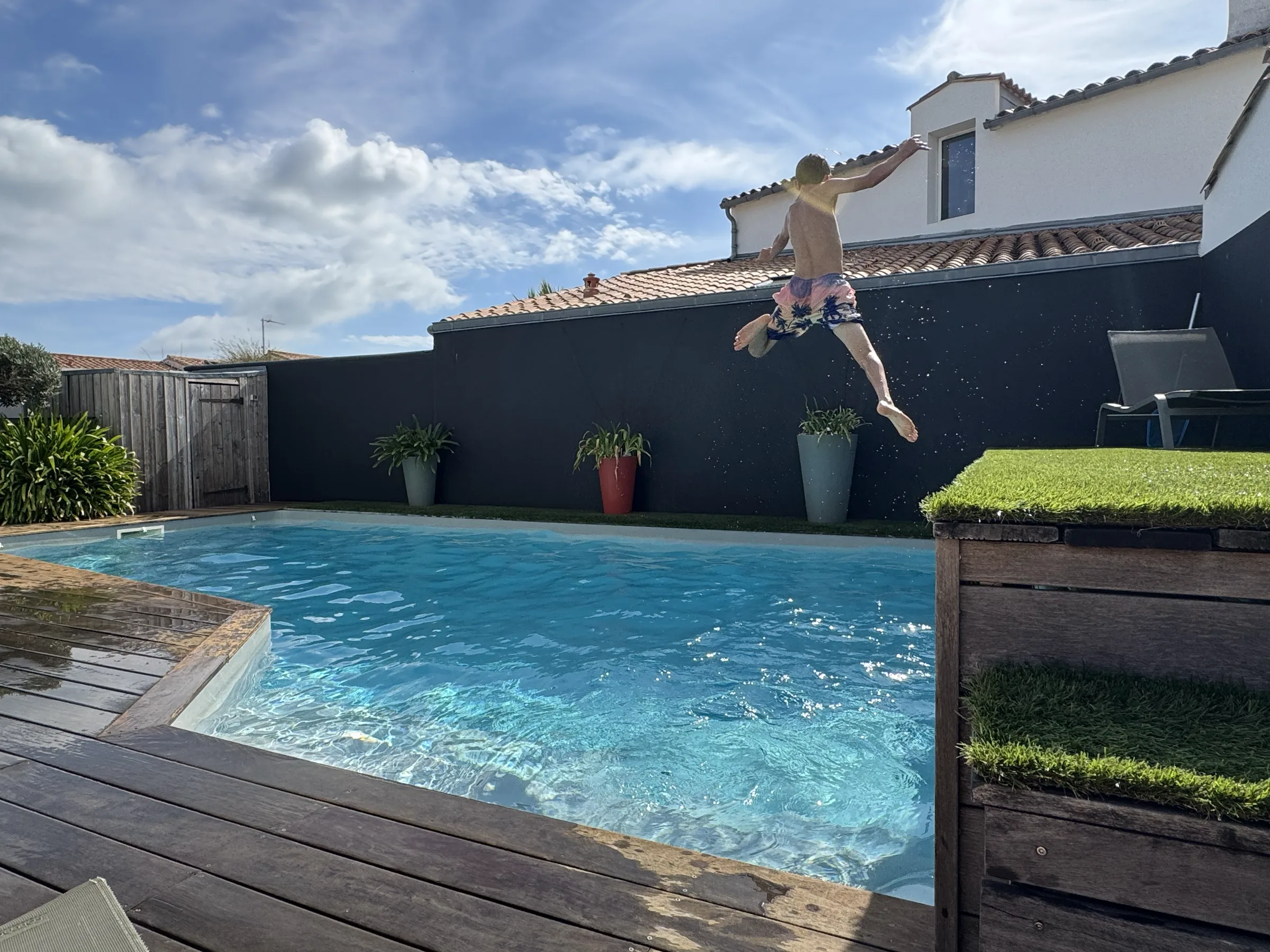 A child leaping off a wall into a swimming pool on a sunny day
